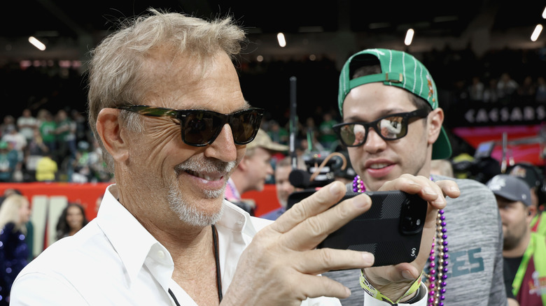 Kevin Costner holding up his phone by Pete Davidson