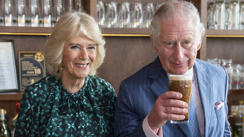 King Charles holding pint of Guinness with Queen Camilla