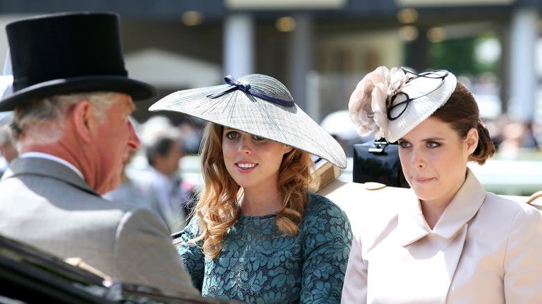 King Charles standing in front of Princesses Eugenie and Beatrice