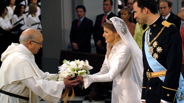 Letizia Ortiz hands her bouquet to a priest