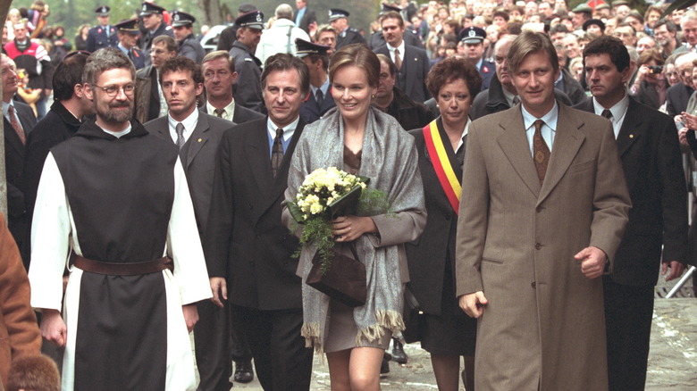 Young Queen Mathilde and Prince Philippe walking in crowd