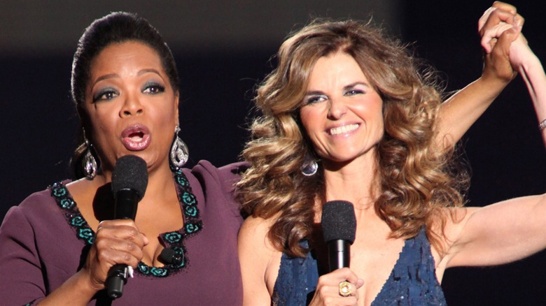 Oprah holding up Maria Shriver's hand