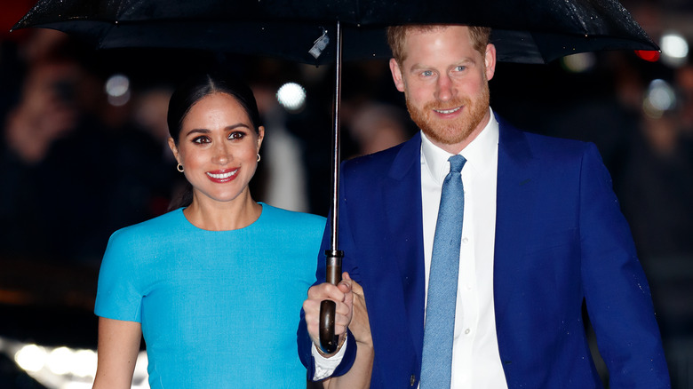 Meghan Markle, Prince Harry holding umbrella