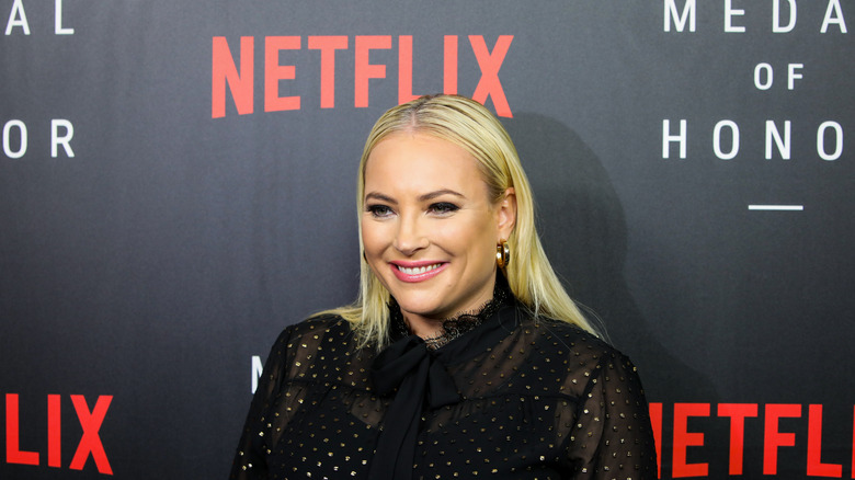 Meghan McCain smiles in front Netflix banner