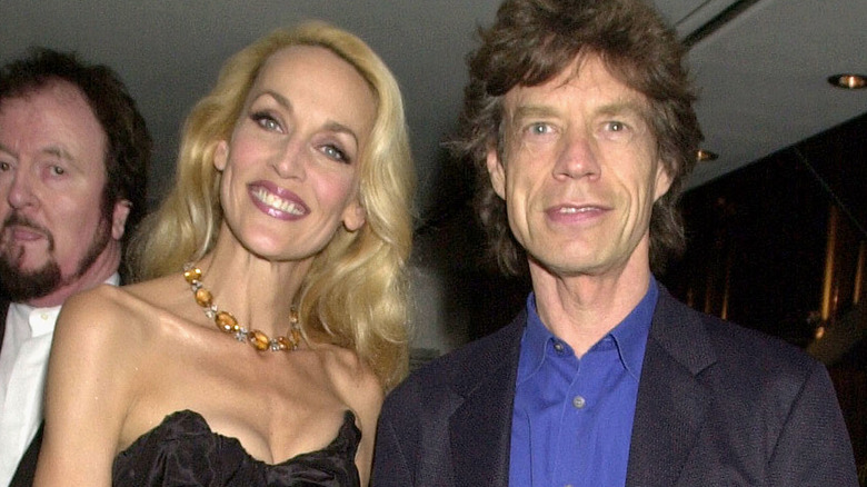 Jerry Hall wears a black strapless gown beside Mick Jagger.