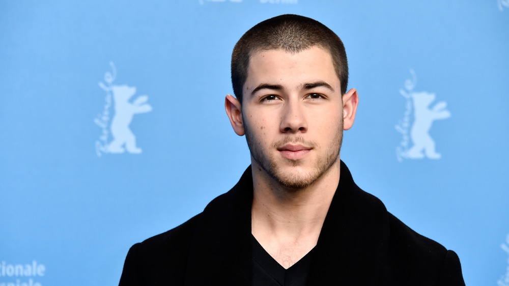 Nick Jonas looking serious in black coat