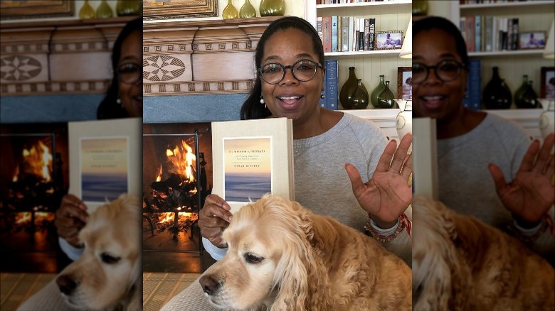 Oprah Winfrey holding book next to dog