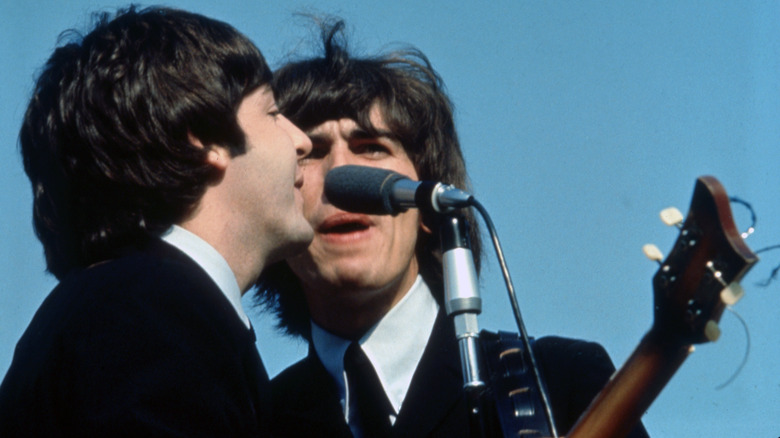 Paul McCartney, George Harrison performing on stage