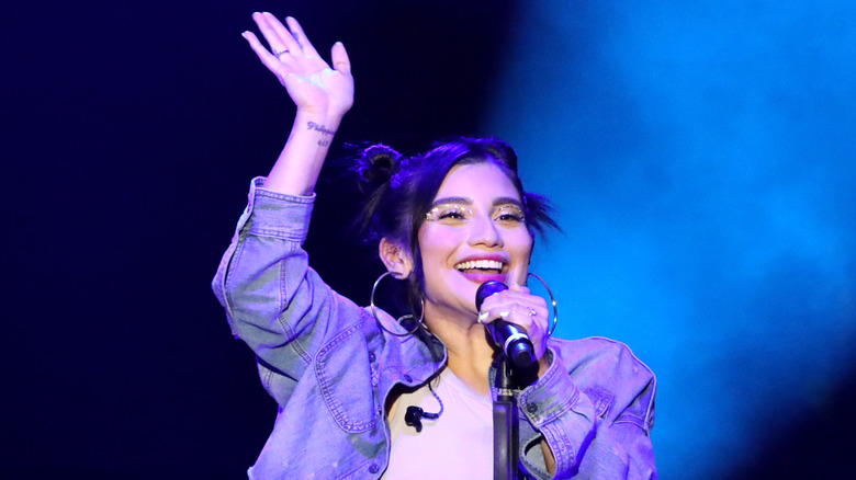 Kirstin Maldonado holding microphone smiling waving