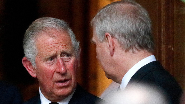 Prince Charles looks speaking to Prince Andrew