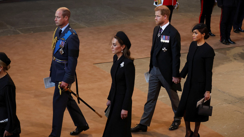 Harry and Meghan at the funeral holding hands 