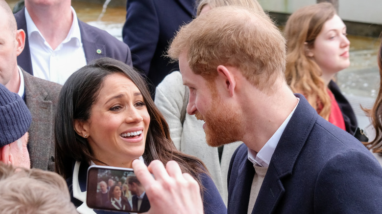 Prince Harry and Meghan Markle smiling in crowd