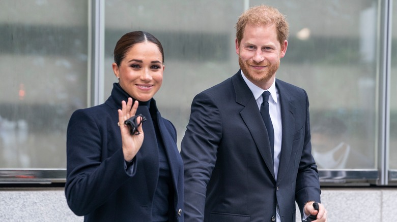 Prince Harry and Meghan Markle smiling and waving