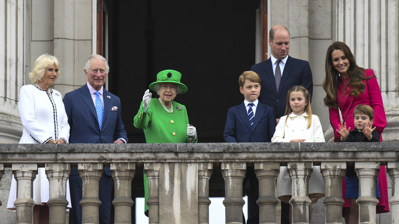 Members of the British royal family smiling and waving on Buckingham Palace balcony