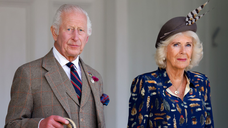 King Charles and Queen Camilla standing next to each other in formal country attire