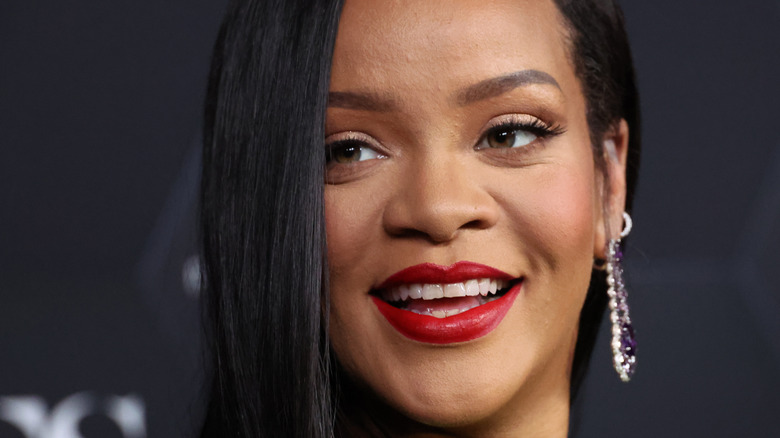 Rihanna smiling, wearing red lipstick
