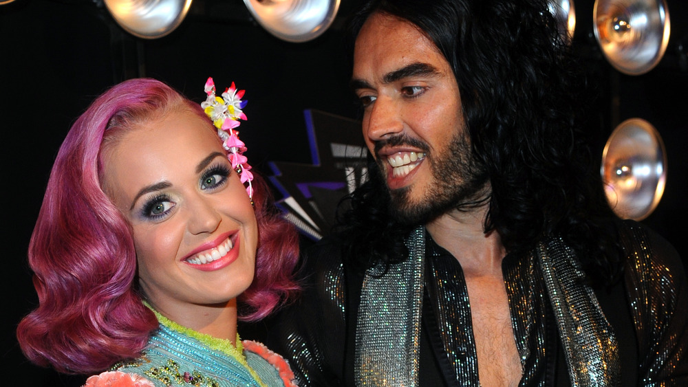 Katy Perry smiling as Russell Brand gazes at her and smiles back 