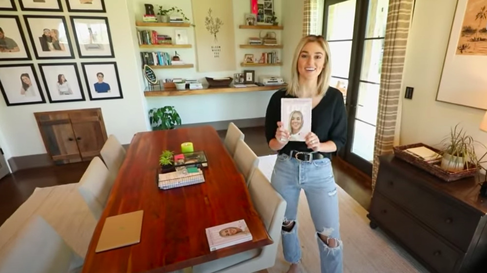 Sadie Robertson holding up a book in the office of her home