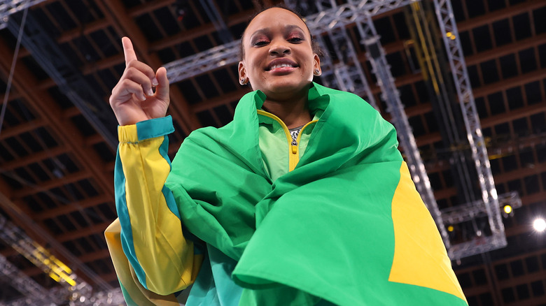 Rebeca Andrade raising finger & wrapped in Brazil flag