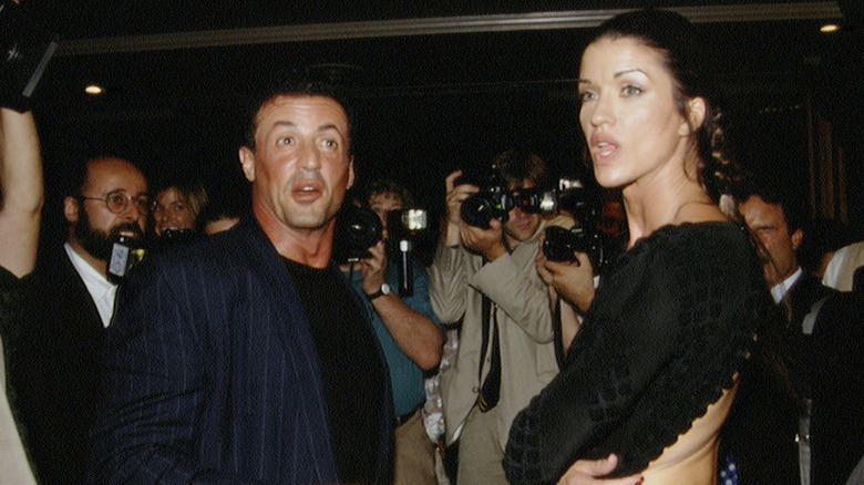 Sylvester Stallone and Janice Dickson talking while surrounded by photographers