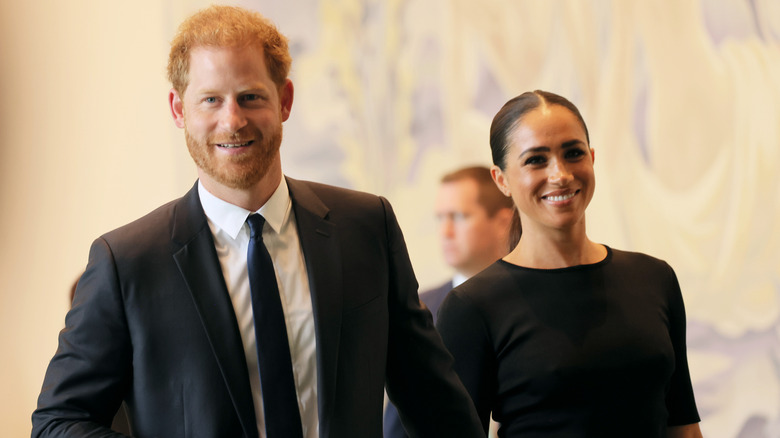 Harry and Meghan smiling while walking 