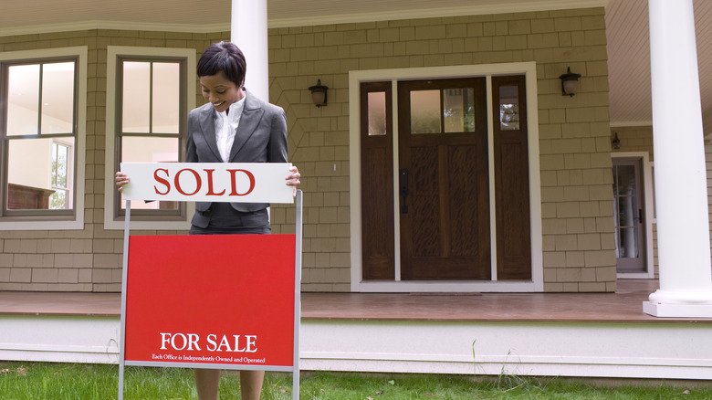 Woman putting a sold sign at a house