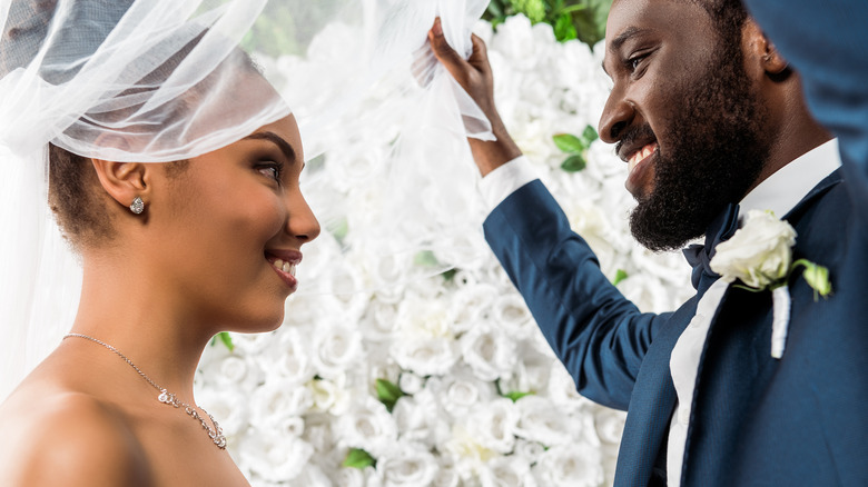 Groom lifts veil off bride's face