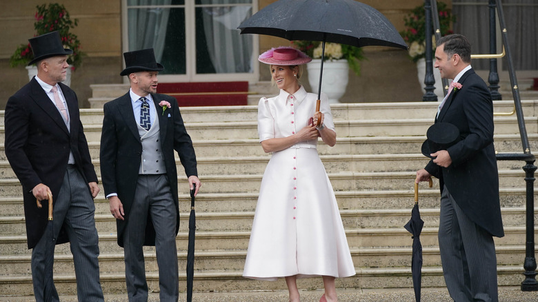 Zara Tindall talking to husband and friends under umbrellas