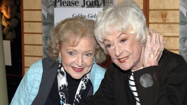 Betty White and Bea Arthur leaning in close together and smiling