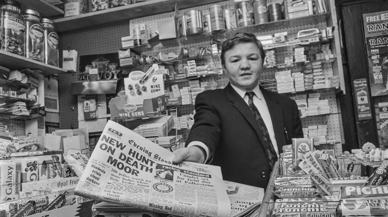 Newspaper stand with man handing out newspaper