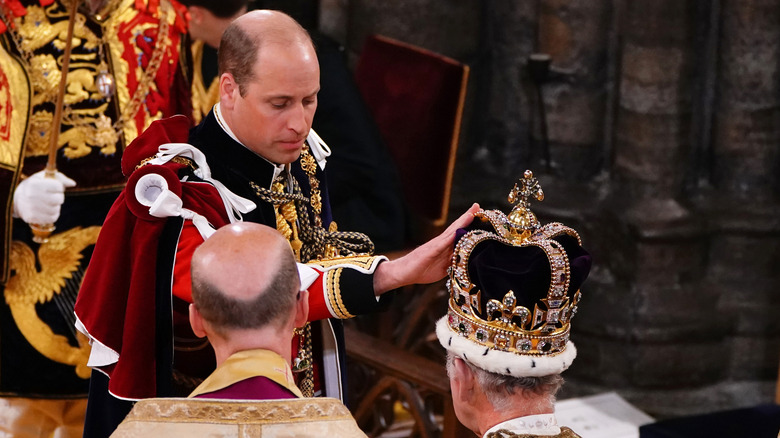 Prince William touching King Charles' crown