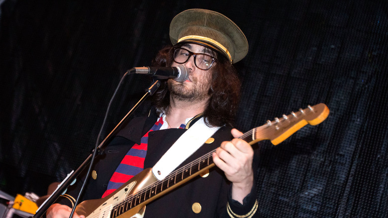 Sean Lennon playing guitar in a hat