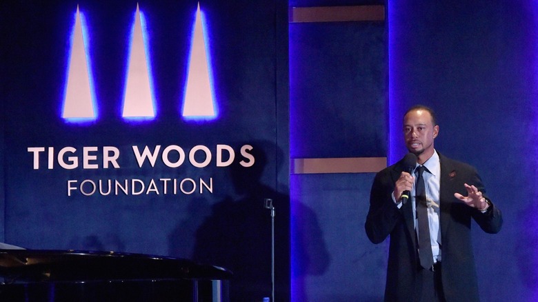 Tiger Woods speaking in front of his foundation logo