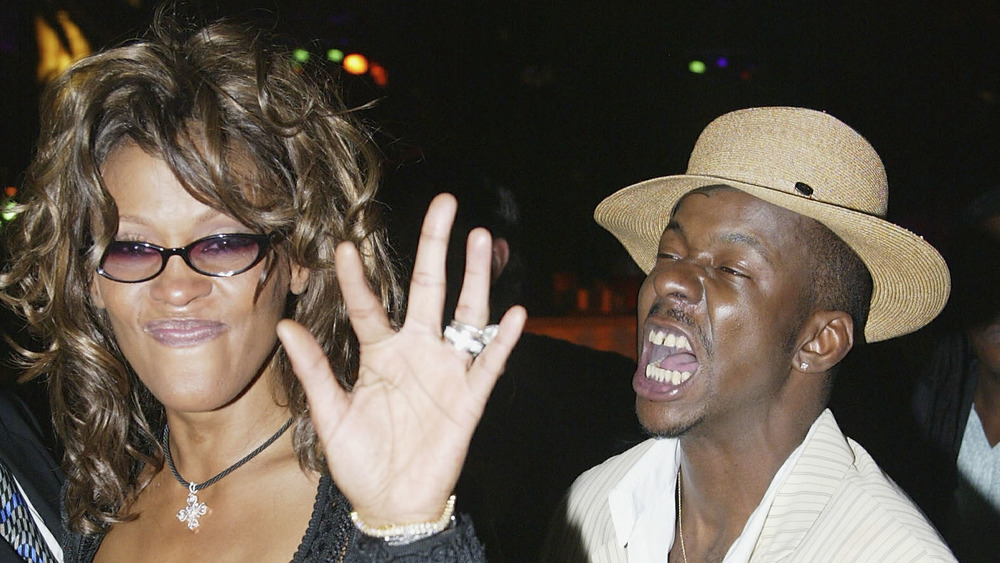 Whitney Houston in glasses and Bobby Brown wearing a hat 