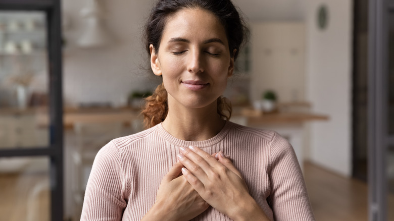 woman folding hands over heart