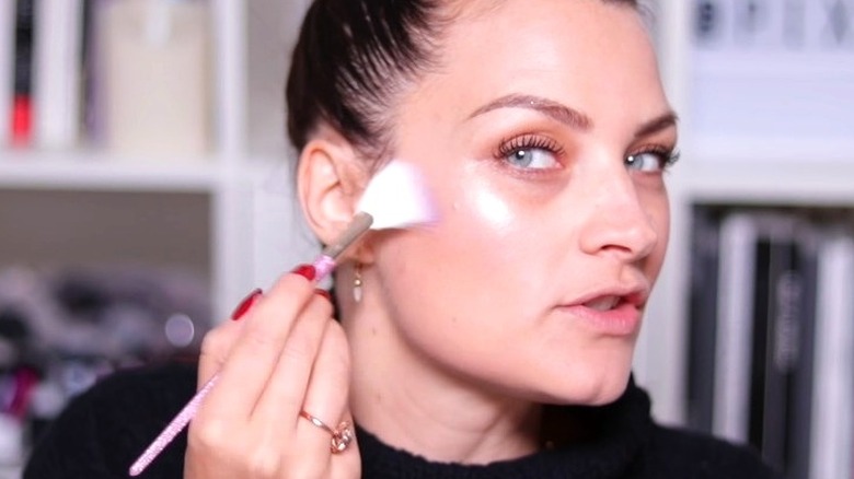 woman applying highlighter with fan brush