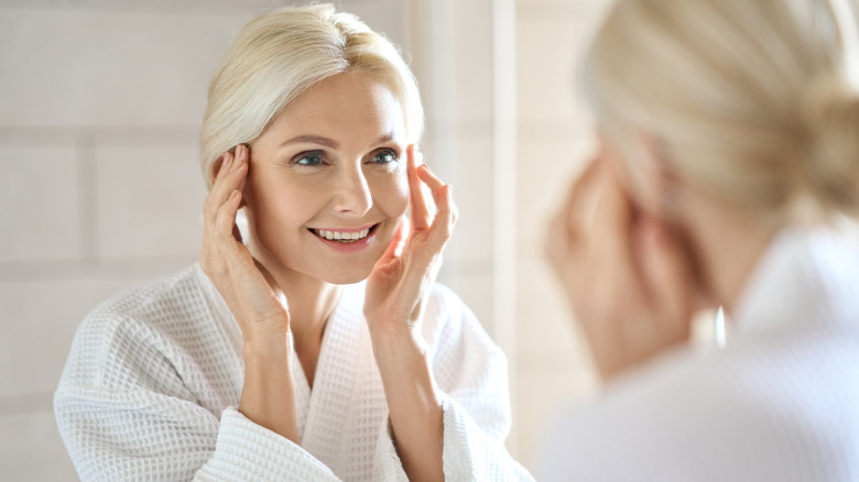 Woman smiles at face in mirror