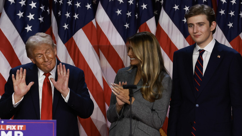 Barron Trump smiling in a suit next to his parents