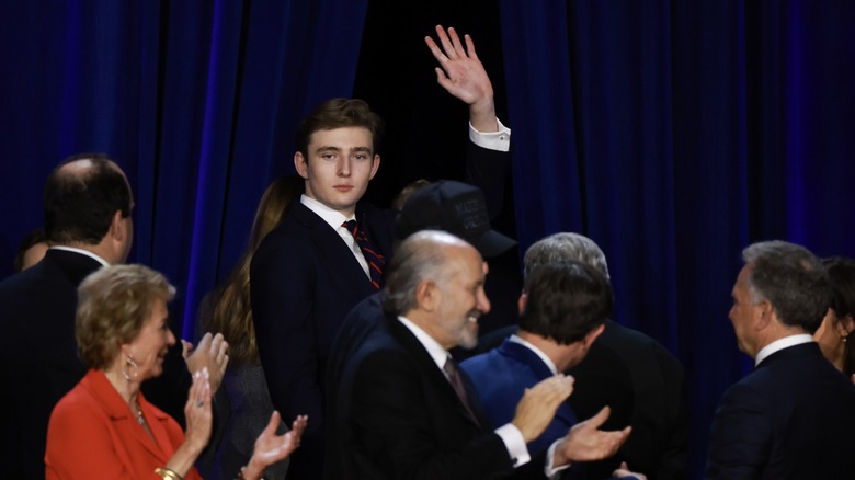 Barron Trump waving, towering over shorter people