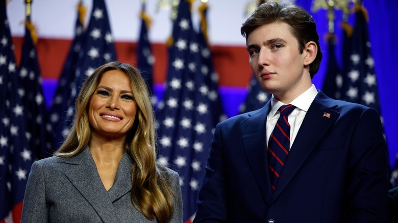 Melania Trump standing next to Barron Trump in front of American flags