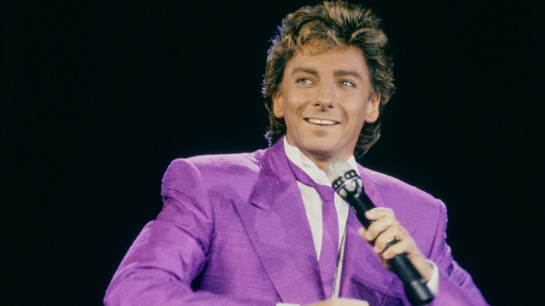 Barry Manilow holding microphone wearing purple suit