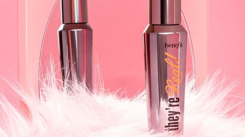 A tube of Benefit Cosmetics Mascara in front of a mirror 