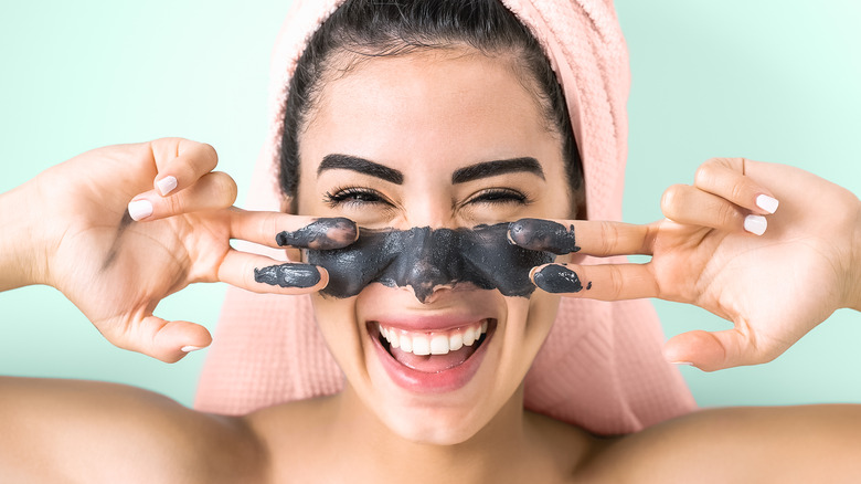 Woman applying charcoal face wash to her face