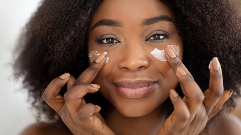 Woman putting on facial moisturizer