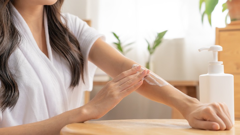 Woman putting lotion on her arm