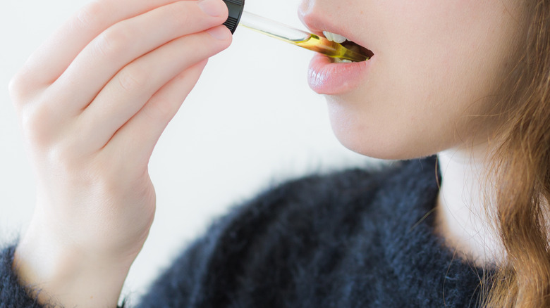 Person putting CBD oil under tongue