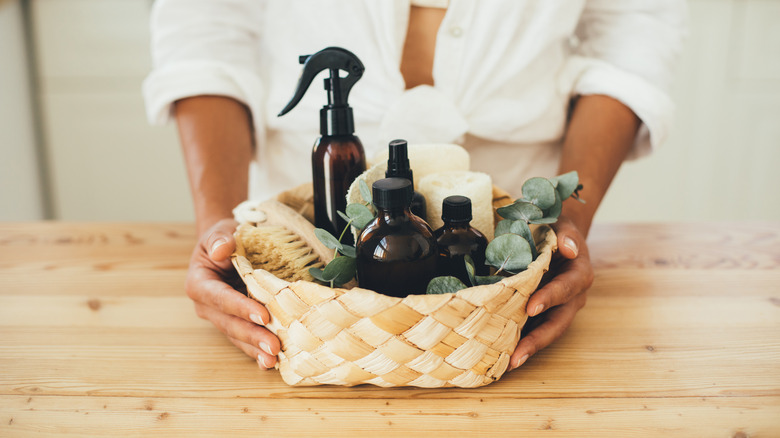 woman's hands holding cleaning supplies