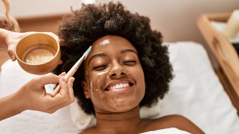 Black woman smiling while getting a facial 