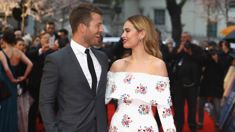 Glen Powell and Lily James smiling on red carpet