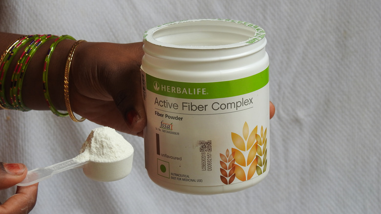 Woman holding a Herbalife fiber supplement in her hand